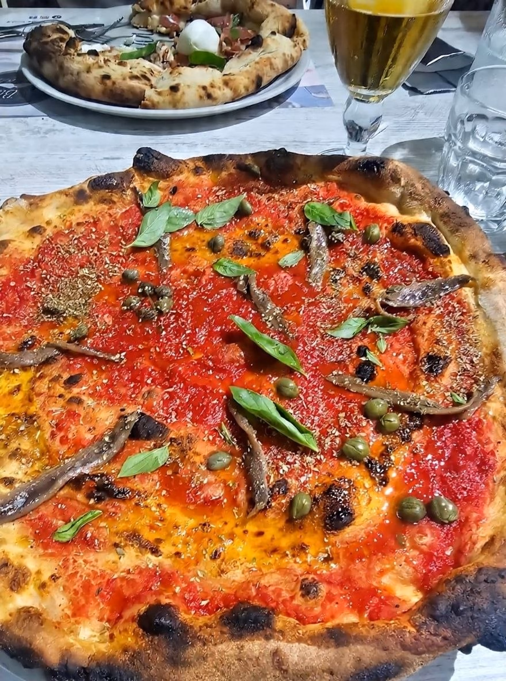 Pizza ruota di carro de Arte Bianca con tomate, anchoas, alcaparras y albahaca
