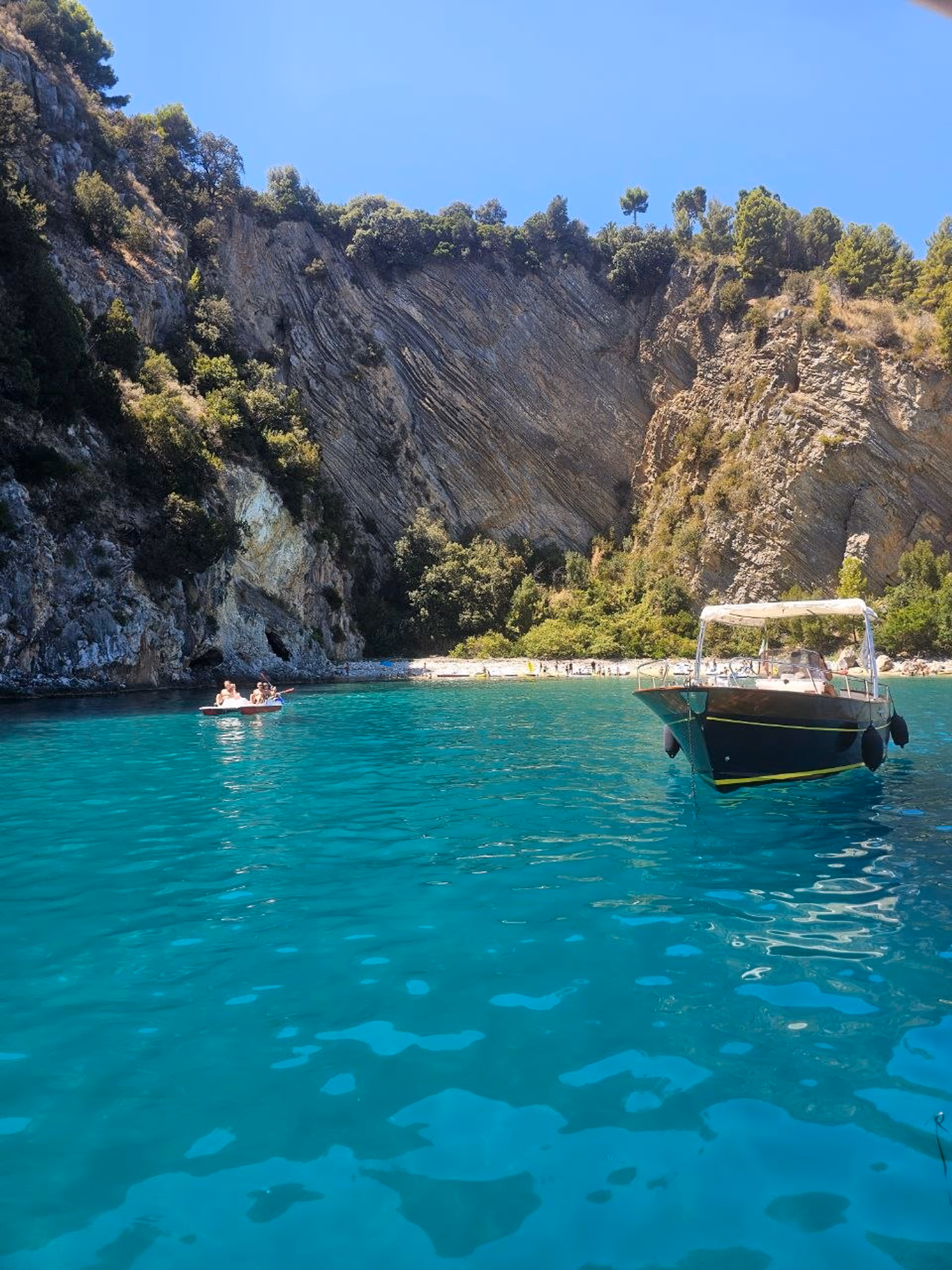 Bucht im Cilento mit tuerkisem Wasser und einem Boot nahe der Kueste